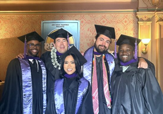 Five architecture students from NewSchool of Architecture of Design stand together and smile in their graduation cap and gowns.