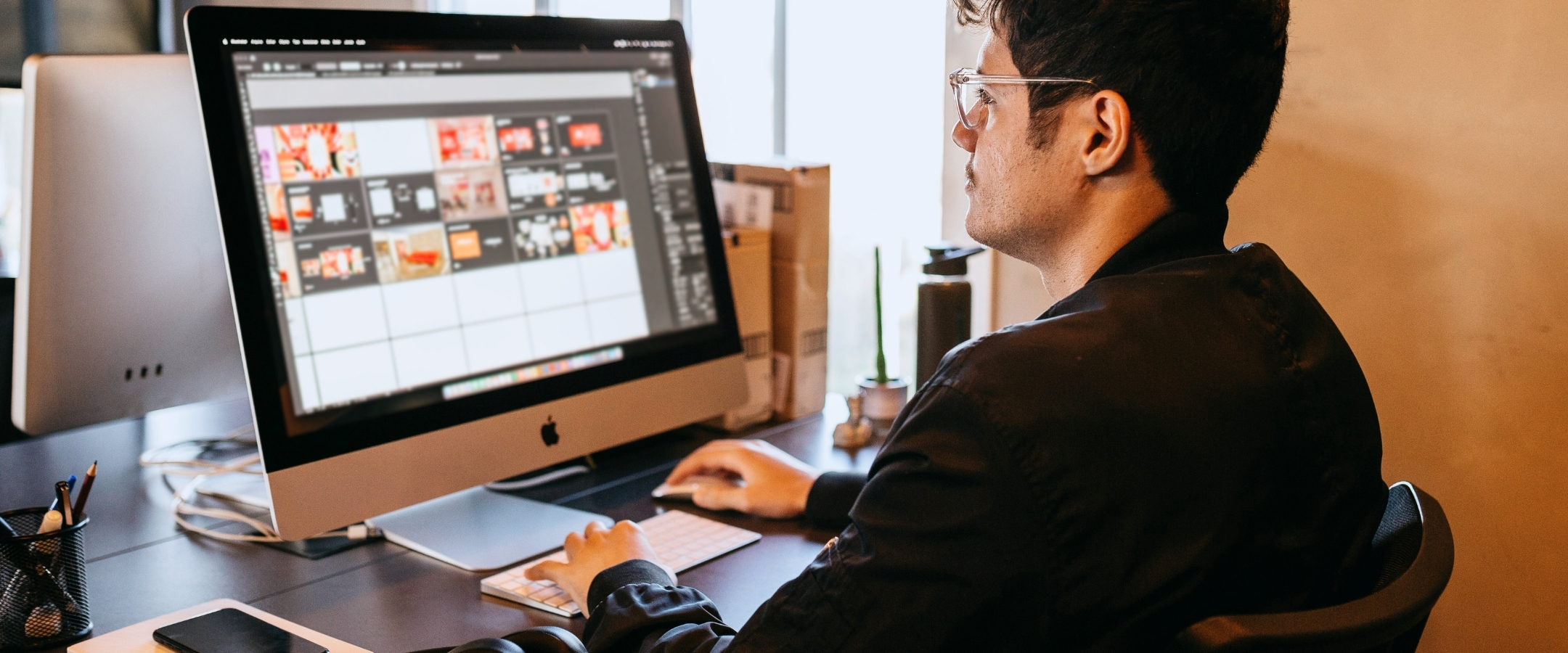 Man works on a desktop computer with a design application open