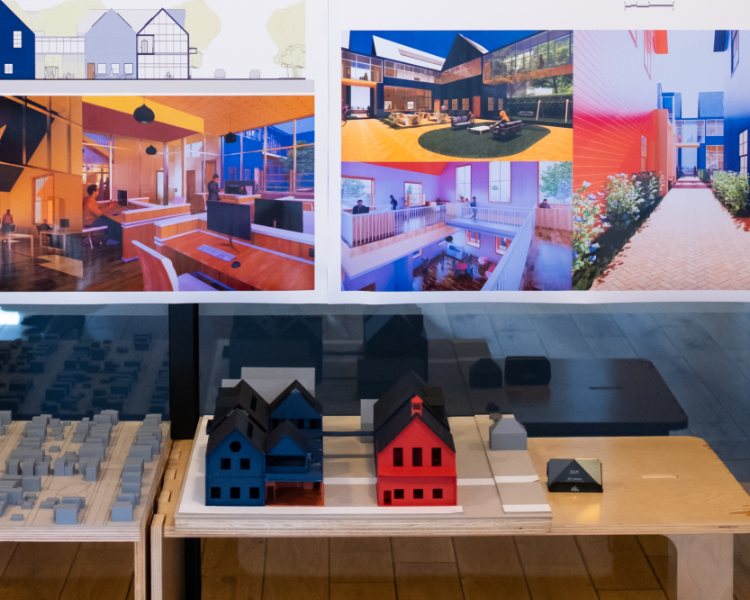 Top half of the photo shows a poster of renderings for a coworking building design. The bottom half shows two models of the coworking space designed by a graduate architecture student at NewSchool of Architecture & Design