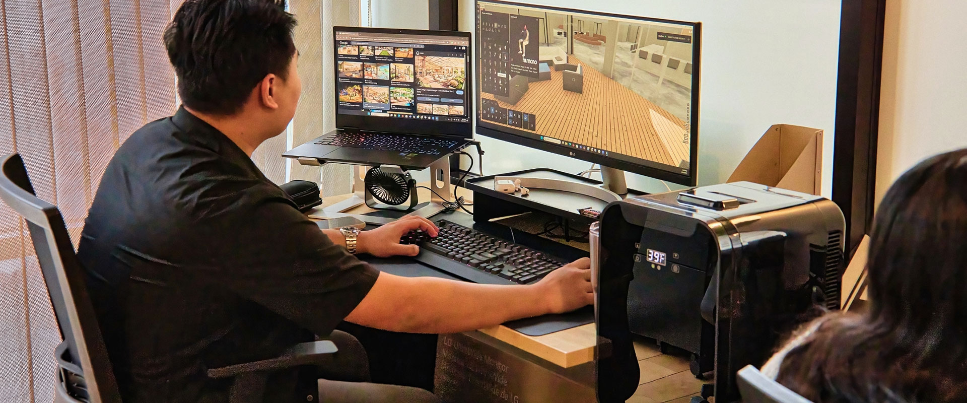 Guy sits at desk and works on dual screens designing the interior of a building.