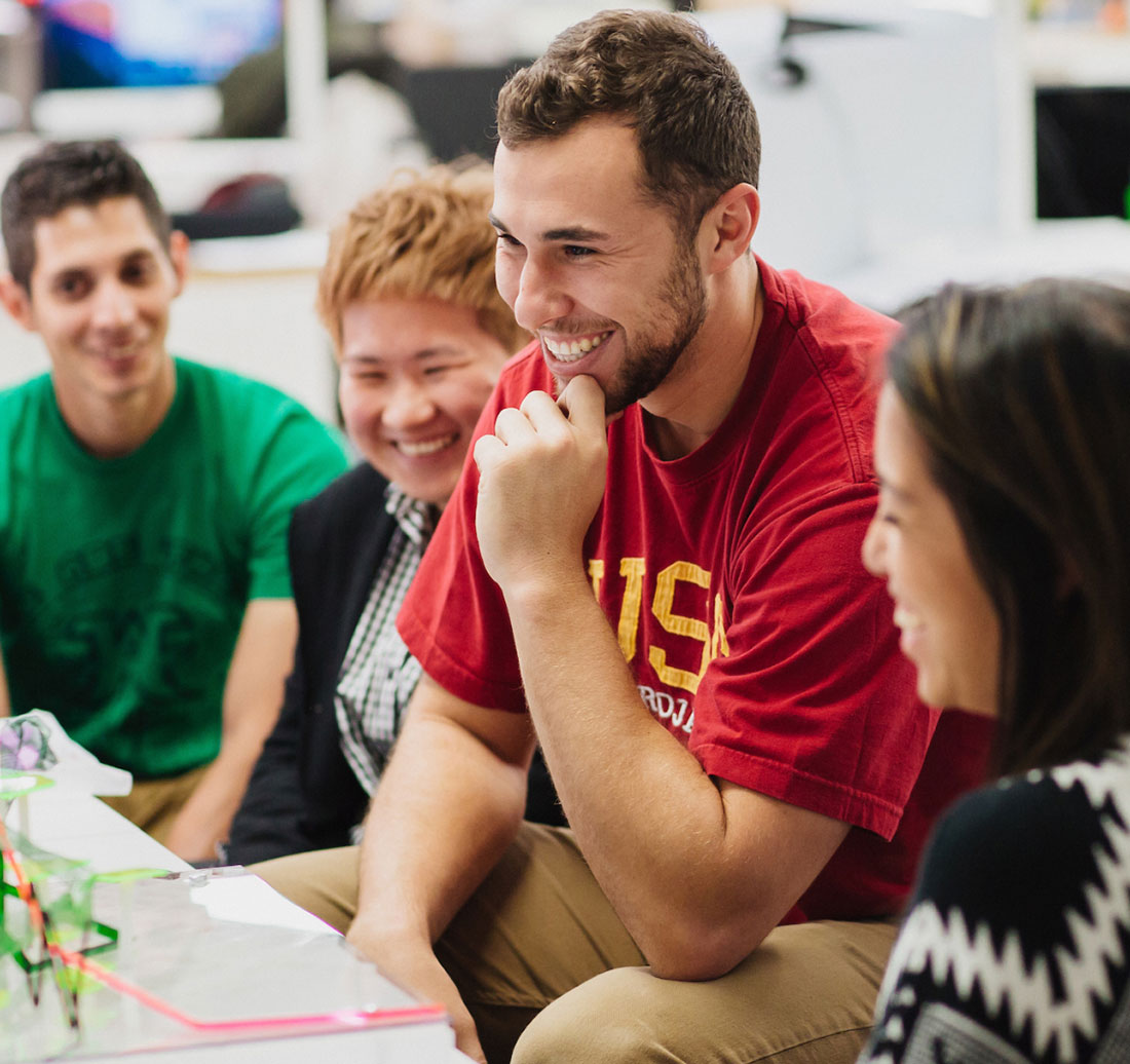A group of students smiling and looking at a architectural model