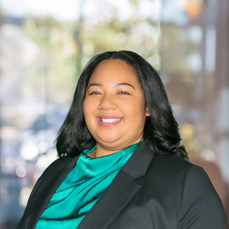 a close up of Maia, wearing an emerald green blouse and smiling