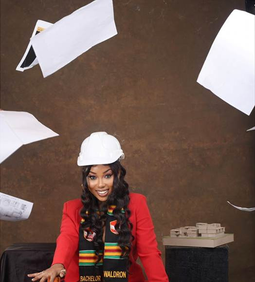 Waldron Adebrah, wearing a white hard hat and smiling, surrounded by flynig papers
