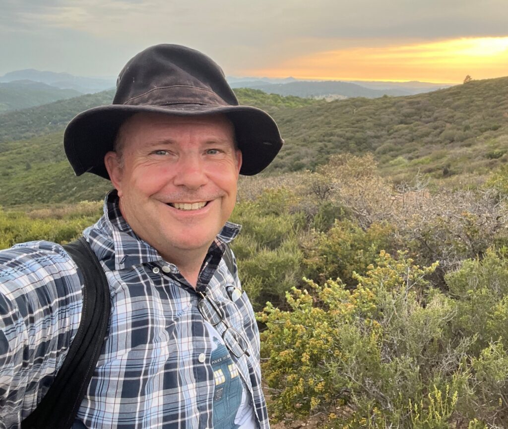 Fred Besancon smiling in a field at sunset